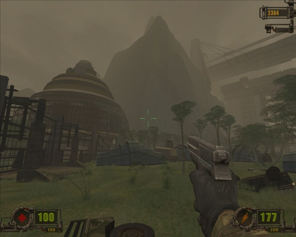 Vivisector: Beast Within (Windows) screenshot: Giant domed buildings and military bunkers nestle in a mist-shrouded valley.