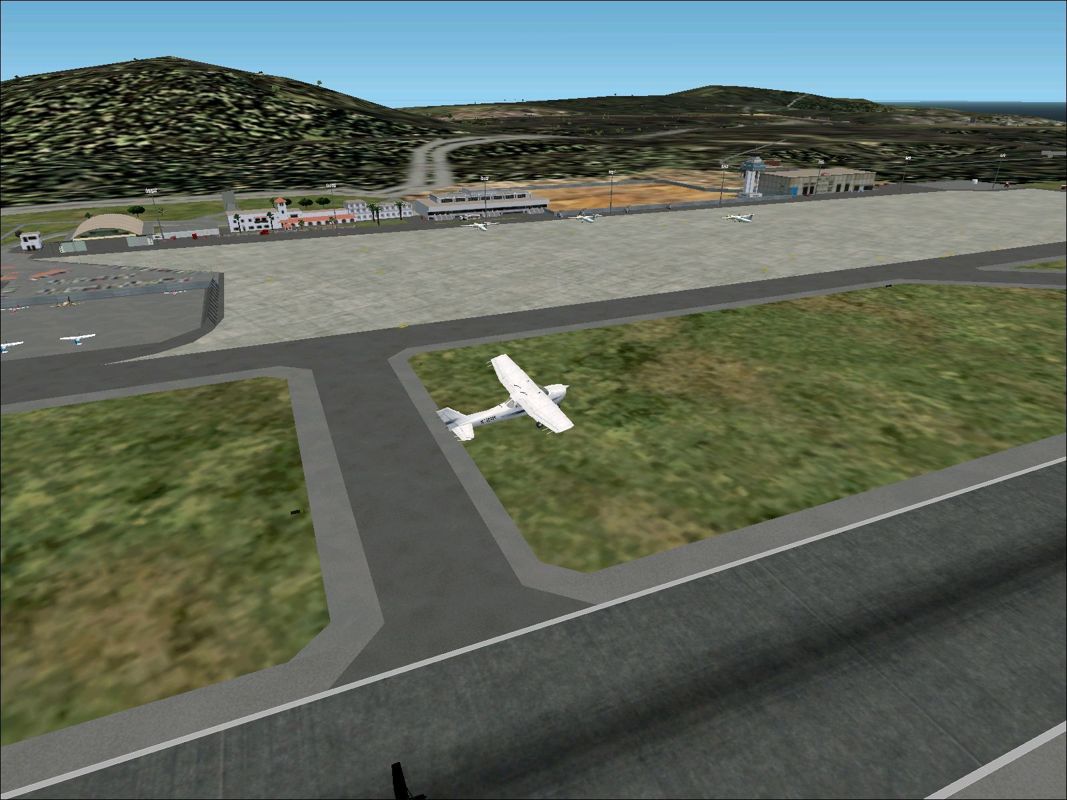 Scenery Spain 3: Canary Islands (Windows) screenshot: Los Rodeos / Tenerife North shortly after take-off showing buildings and static aircraft Flight Simulator 2002