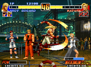 The King of Fighters '96 (Neo Geo) screenshot: Aiming to hit-damage a recovering Mature successfully, Andy Bogard executes his Shouryuu Dan move.