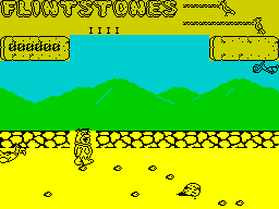 Yabba Dabba Doo! (ZX Spectrum) screenshot: In the first part of the game Fred must pick up the little rocks and drop them into a rubbish pit, clearing the ground so that he can build a house with the big rocks