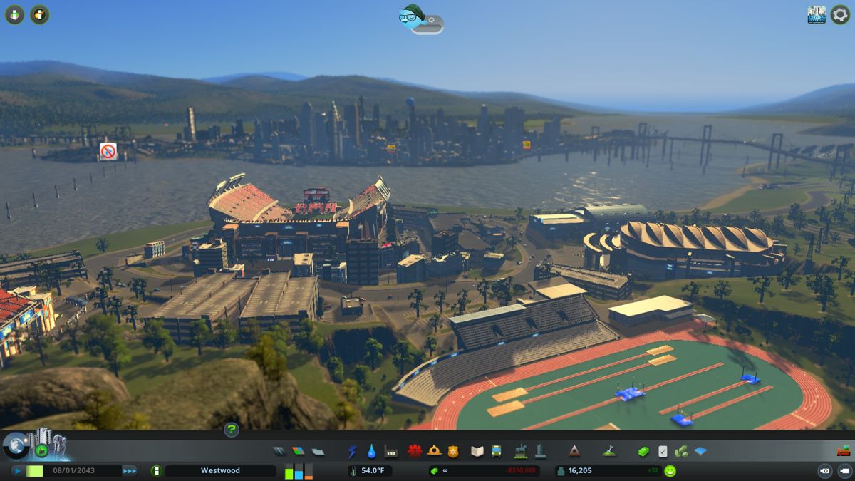 Cities: Skylines (Windows) screenshot: Sun setting over the Olympic park and sports center, with the downtown bay in the background.