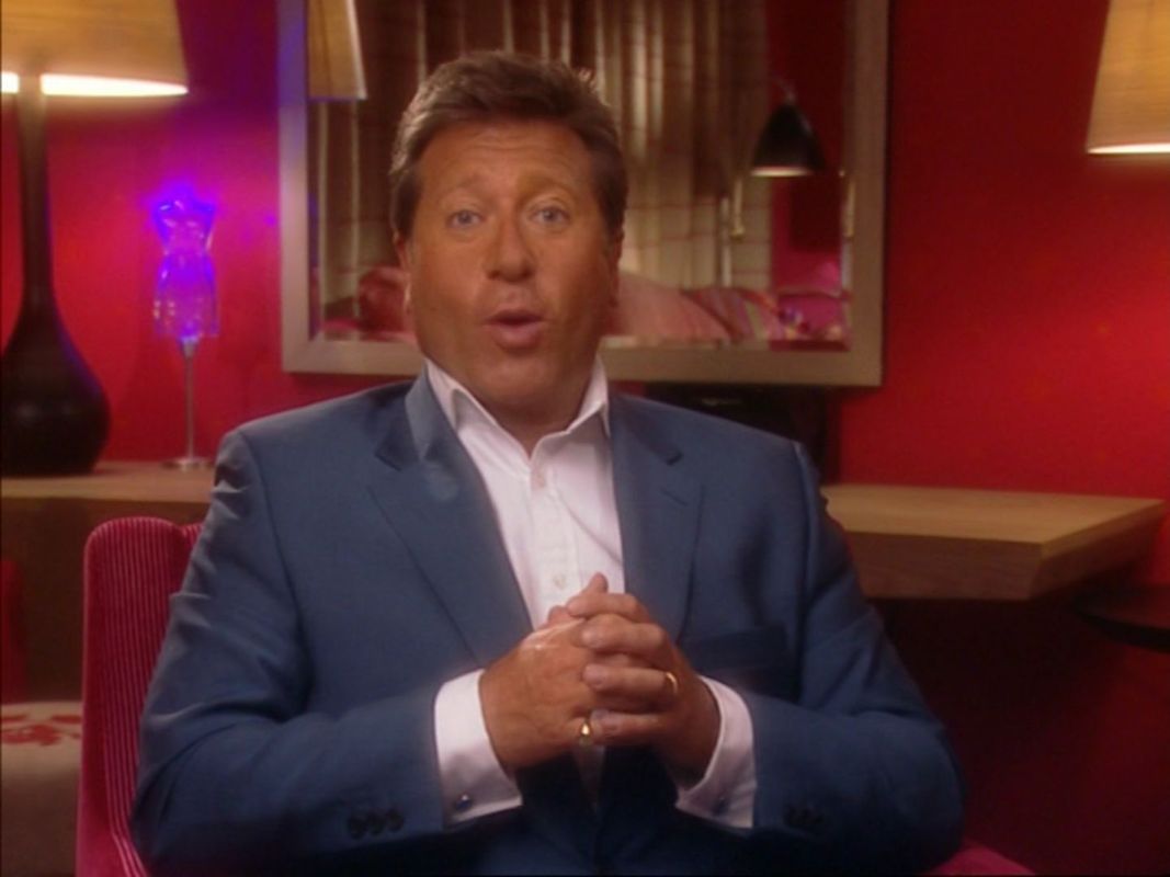 The Greatest TV Trivia Quiz (DVD Player) screenshot: This is the host Neil Fox doing the game's introduction. He appears elsewhere, always in the same chair and in the same suit so there's no need to show him in other parts of the game
